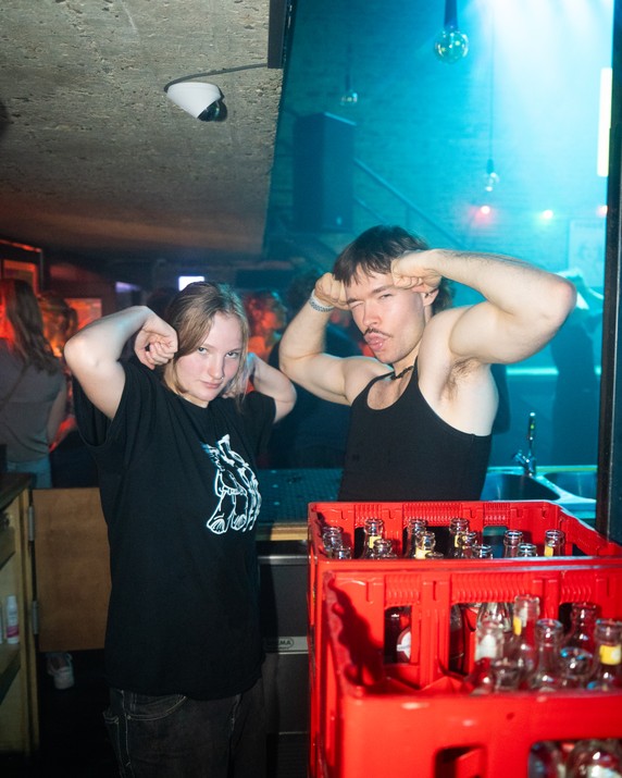 Two people posing beside a crate of bottles